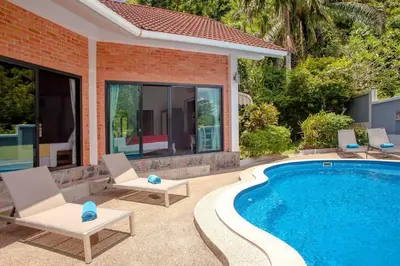 a swimming pool with two chairs next to a house at Villa with private pool and mountain views in Ban Khlong Son
