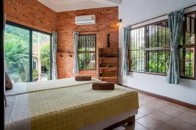 a bedroom with a bed in a room with windows at Villa with private pool and mountain views in Ban Khlong Son