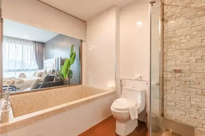 a bathroom with a toilet and a large mirror at Majestic 2BR Residence with garden view in Regent in Bang Tao Beach
