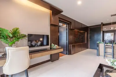 a living room with a television and a white chair at Majestic 2BR Residence with garden view in Regent in Bang Tao Beach