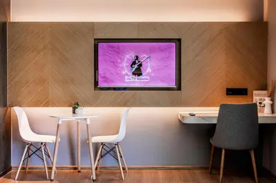 a room with a tv on a wall with a table and chairs at La Vita Phuket by Beringela in Rawai Beach
