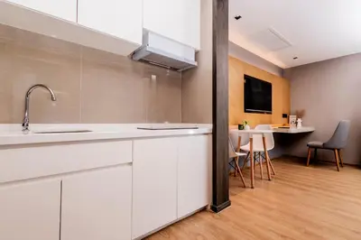a kitchen with white cabinets and a dining room at La Vita Phuket by Beringela in Rawai Beach