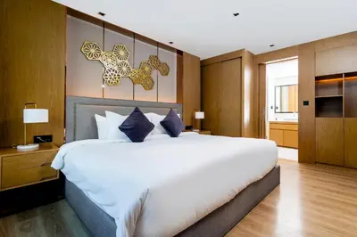 a bedroom with a large white bed with blue pillows at La Vita Phuket by Beringela in Rawai Beach