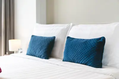 a white bed with two blue pillows on it at Diamond Bangtao Beach 1 bedroom in Bang Tao Beach