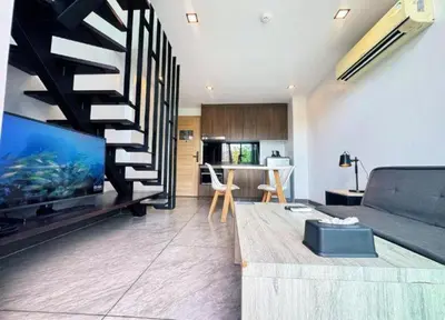 a living room with a couch and a staircase at Utopia Naiharn Loft Condo in Rawai Beach