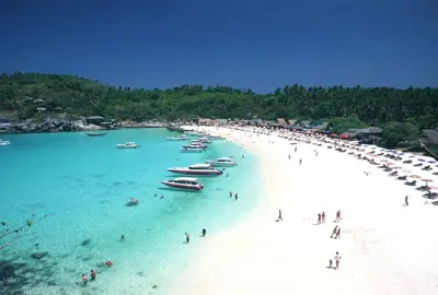 a group of people on a beach with boats in the water at Patong Leisure Hotel in Patong Beach