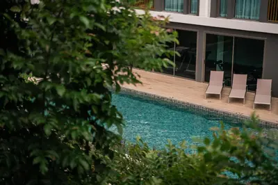 a swimming pool with chairs next to a building at Luxury Ozone Bang Tao 1 Bdr in Laguna Phuket