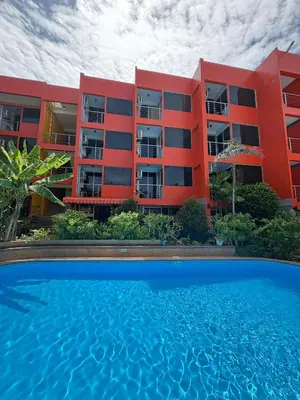 a red building with a swimming pool in front of it at THE PORTERHOUSE Boutique Hotel in Patong Beach