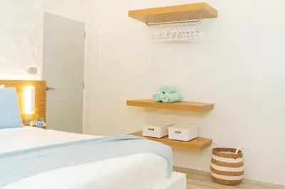 a bedroom with a bed and wooden shelves at Stylish Studio with Pool - 8' walk to Rawai Beach - 