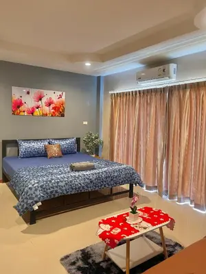 a bedroom with a bed and a table at Pluemjai mansion in Kathu