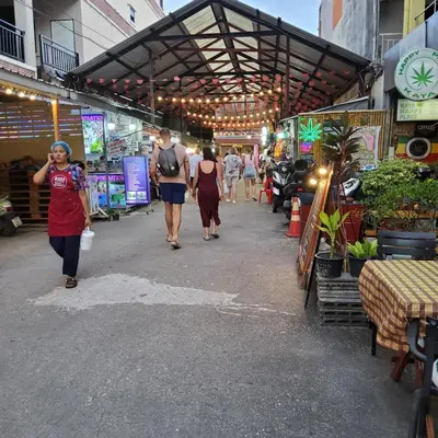 a group of people walking down a street at Flowernight Guesthouse in Kata Beach