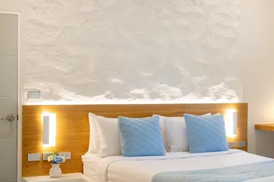 a bedroom with a bed with blue and white pillows at Stylish Studio with Pool - 8' walk to Rawai Beach - 