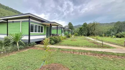 a small green and white house with a yard at Greenview Room and Restaurant
