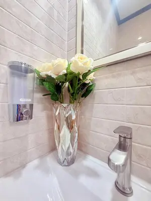 a vase of roses sitting on a bathroom sink at PS House Bangtao in Bang Tao Beach