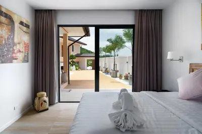 a white angel sitting on a bed in a bedroom at Tilawan Villa by G Estate Phuket in Ban Klang