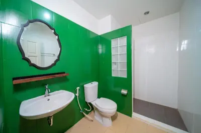 a green bathroom with a toilet and a sink at Nyonya Maison Boutique Hotel Phuket Old Town in Phuket Town