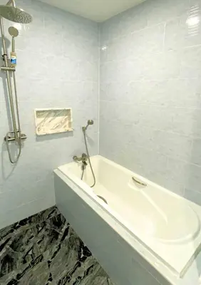 a white bath tub in a bathroom with blue tiles at Chalong pool villa in Ban Na Bon