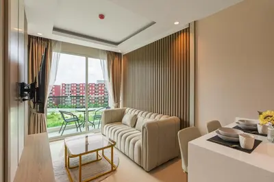 a living room with a couch and a table at Modern 1BR Condo w Balcony Near Central Phuket in Ban Na Khua