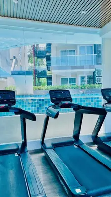 a row of treadmills in a gym with a window at Modern 1BR Condo w Balcony Near Central Phuket in Ban Na Khua