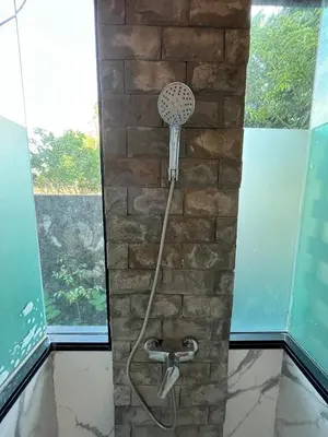 a shower in a room with a stone wall at Rawai Beach Villa in Nai Harn Beach