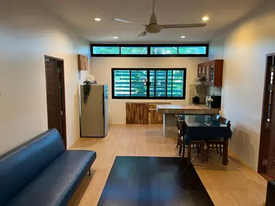 a living room with a blue couch and a kitchen at Rawai Beach Villa in Nai Harn Beach