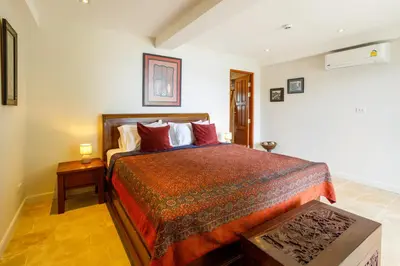 a bedroom with a large bed with red pillows at Seafront Pool Villa Nambo in Ko Taphao Noi