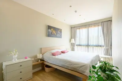 a bedroom with a bed with pink pillows and a window at Diamond Condominium Phuket 2BR 5 min to Bangtao beach in Bang Tao Beach