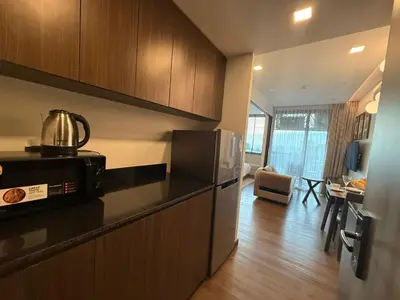 a kitchen with a refrigerator and a table in a room at New 1BR Apartment in The Proud Karon Phuket in Karon Beach