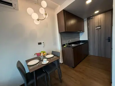a kitchen with a table and chairs and a kitchen with a sink at New 1BR Apartment in The Proud Karon Phuket in Karon Beach