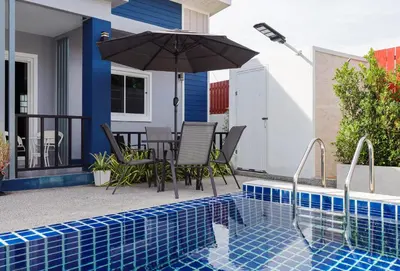 a patio with a table and an umbrella next to a pool at Leema Beach Villa - Bangtao in Ban Thalat Choeng Thale