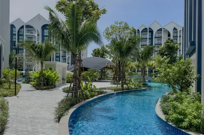 a pool with palm trees in front of a building at Modern 1 & 2 Bedroom Apartments Naiyang Phuket by Mango Family in Nai Yang Beach
