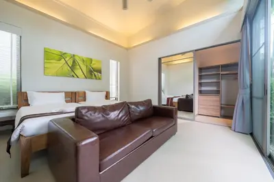 a bedroom with a bed and a leather couch at Mahogany Superb Pool Villa in Pasak in Phuket