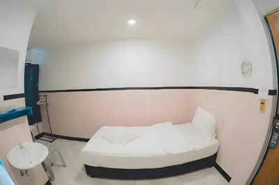 a small white bed in a room with a mirror at xx Mitr Inn - Phuket Old Town มิตรอินน์ ภูเก็ต เมืองเก่า 3 in Phuket Town