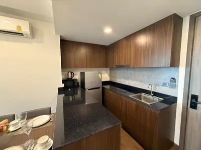 a kitchen with wooden cabinets and a counter top at Cozy 2BR Apartment in The Proud Karon Beach in Karon Beach