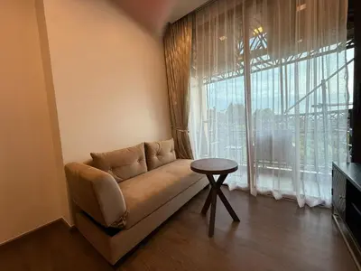 a couch in a living room with a large window at Cozy 2BR Apartment in The Proud Karon Beach in Karon Beach