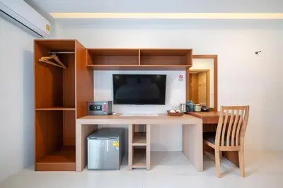 a desk with a television and a chair in a room at Thawalai Inn Kata in Kata Beach