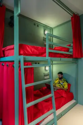 a man sitting on a bed in a bunk bed at Whoopers Hostel Ao Nang - By The Beach in Ban Khlong Haeng