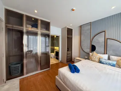 a bedroom with a large bed with blue pillows on it at Bellevue Bangtao 2 bedrooms in Laguna Phuket