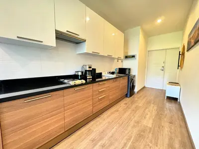 a kitchen with white cabinets and a wooden floor at Veloche Peaceful Condo In Karon Beach in Karon Beach