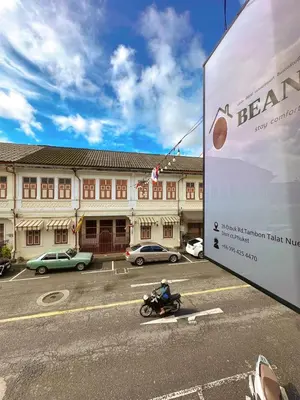 a man riding a motorcycle in front of a building at Beanstay hostel in Phuket Town