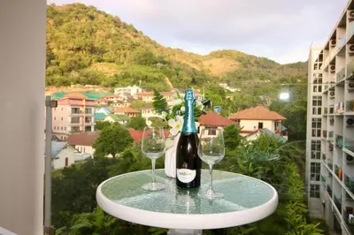 a bottle of wine and two glasses on a table on a balcony at Chic Condominium A 518 in Karon Beach