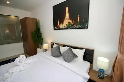 a bedroom with a white bed with a tv on the wall at Chic condominium A4 floor in Karon Beach