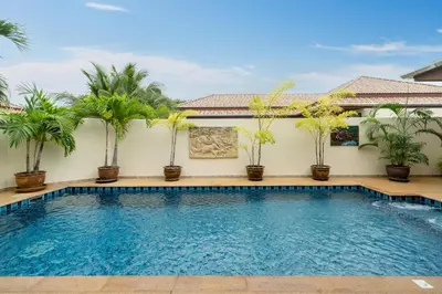 a swimming pool in front of a house with palm trees at Rawai Beach Villa in Rawai Beach