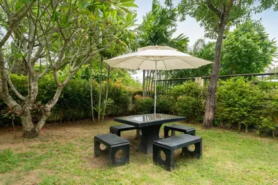 a picnic table with two benches and an umbrella at Rawayana Beach Villa 3D14 in Phuket Town