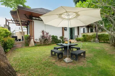 a table and bench with an umbrella in a yard at Rawayana Beach Villa 3D14 in Phuket Town