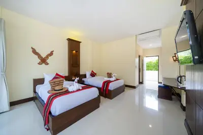 a hotel room with two beds and a flat screen tv at JR Siam Inn Resort in Kata Beach