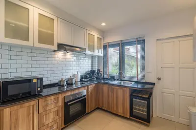 a kitchen with wooden cabinets and a microwave at Bee Villa Wellness Resort Phuket in Laguna Phuket