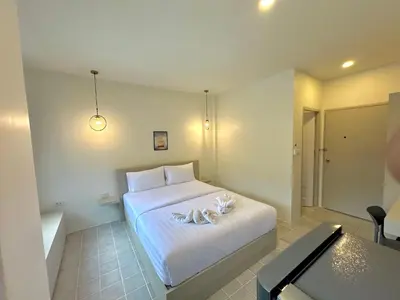 a bedroom with a white bed and a table at Kata Platinum in Kata Beach