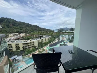 a balcony with a chair and a view of a resort at Twin Sand Phuket by PPR in Patong Beach