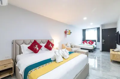 a bedroom with a large bed and a living room at Phuket Leisure Time Hotel in Rawai Beach
